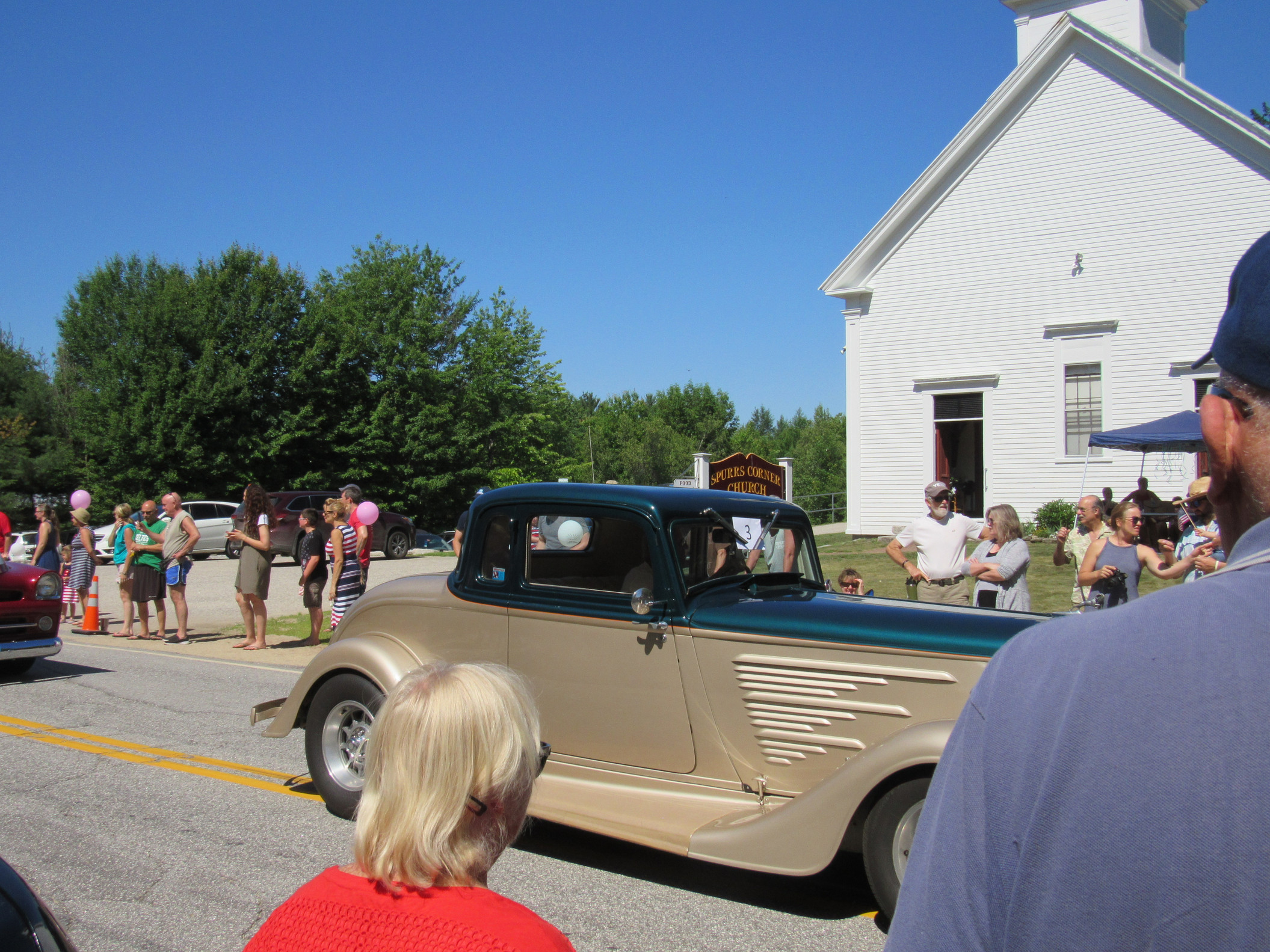 Antique passenger car passing parade spectators at the Fourth of July parade.