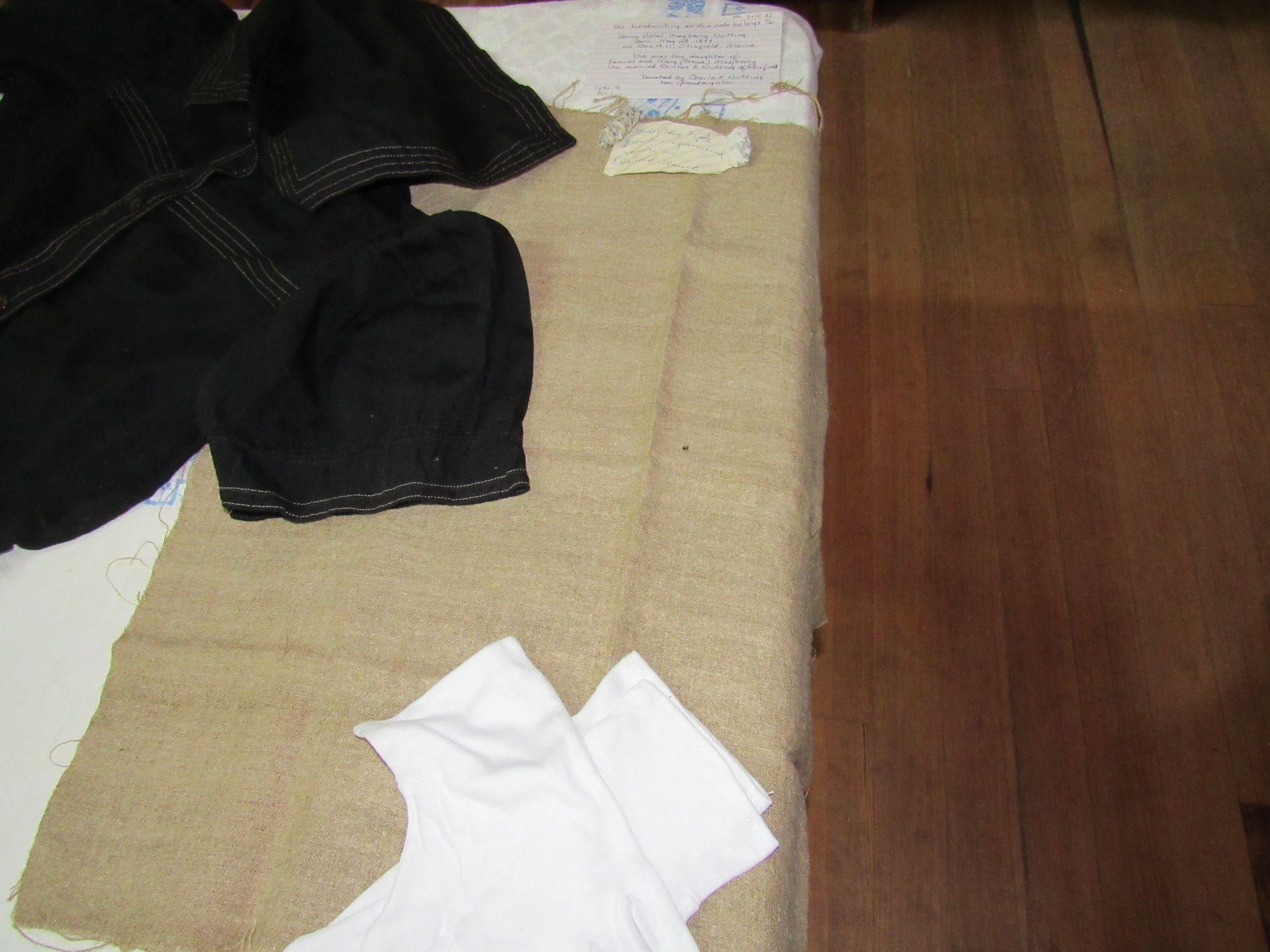 Flax textile and clothing display with handwritten identification cards.