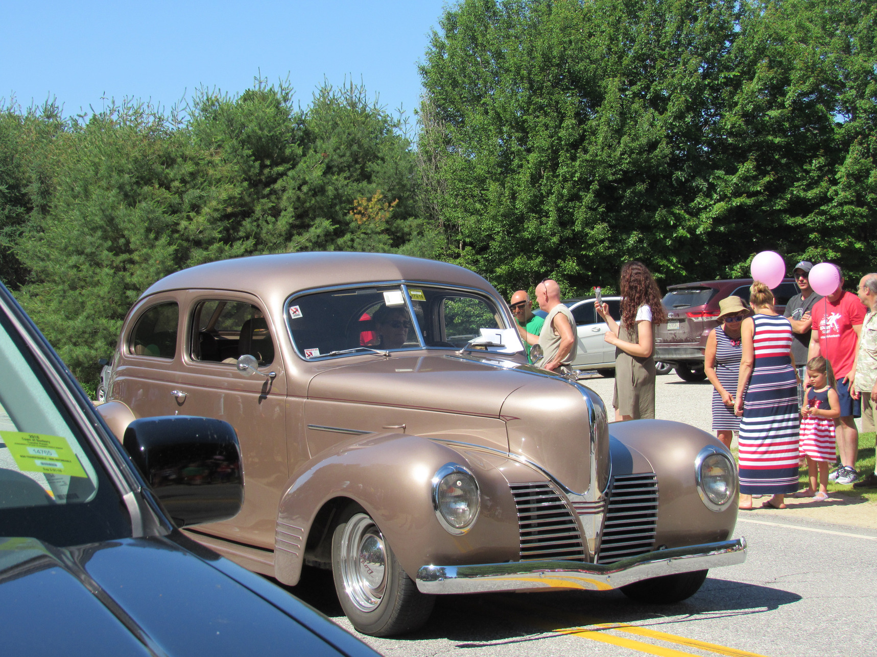 Antique passenger car passing parade spectators at the Fourth of July parade.