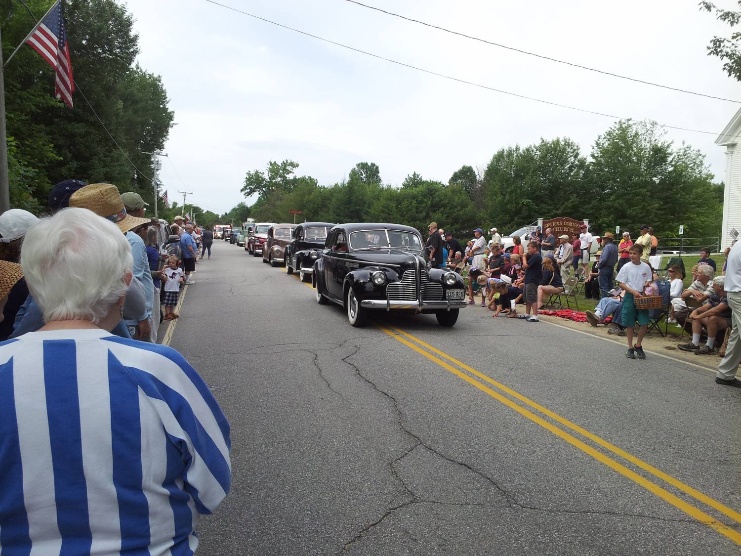 Antique passenger car passing parade spectators at the Fourth of July parade.