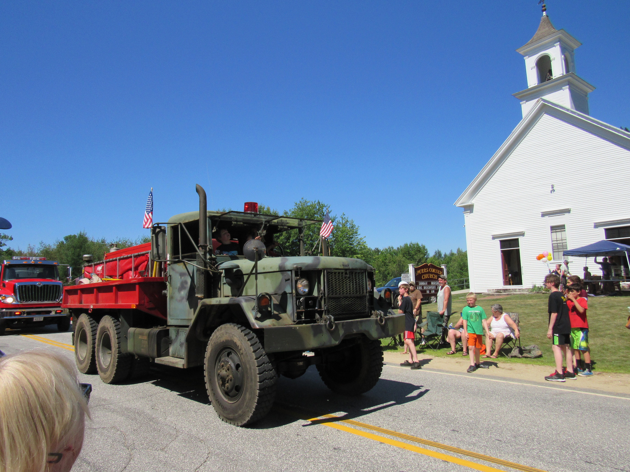Camouflage truck with a red equipment bed at the Fourth of July parade.