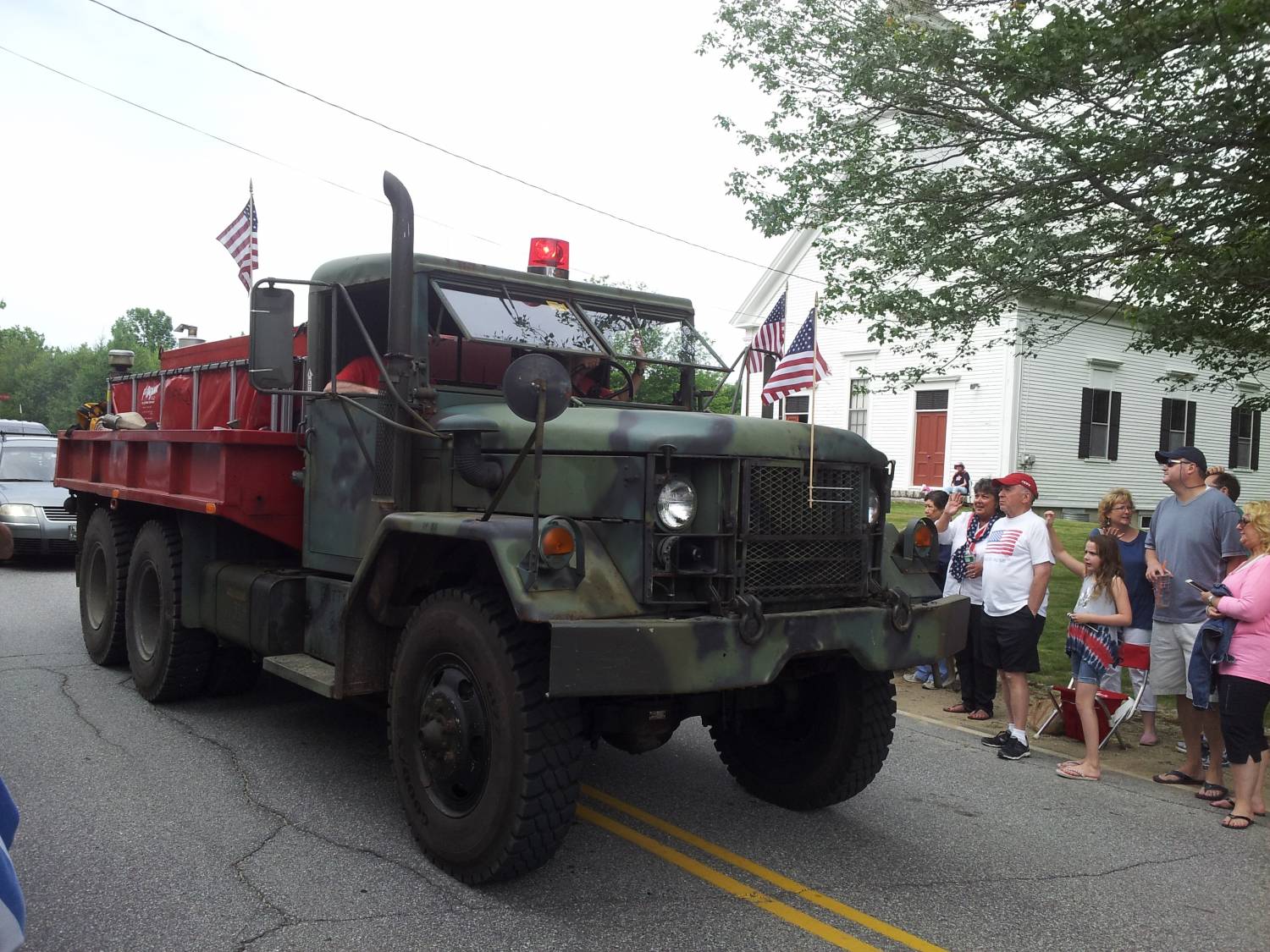 Camouflage truck with a red equipment bed at the Fourth of July parade.