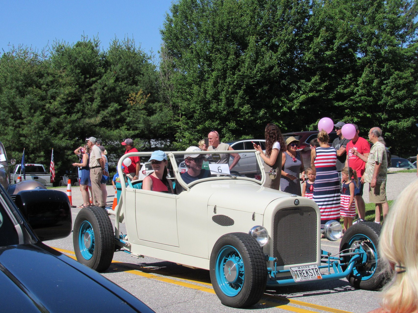White open-top hot rod with blue wheels at the Fourth of July parade.