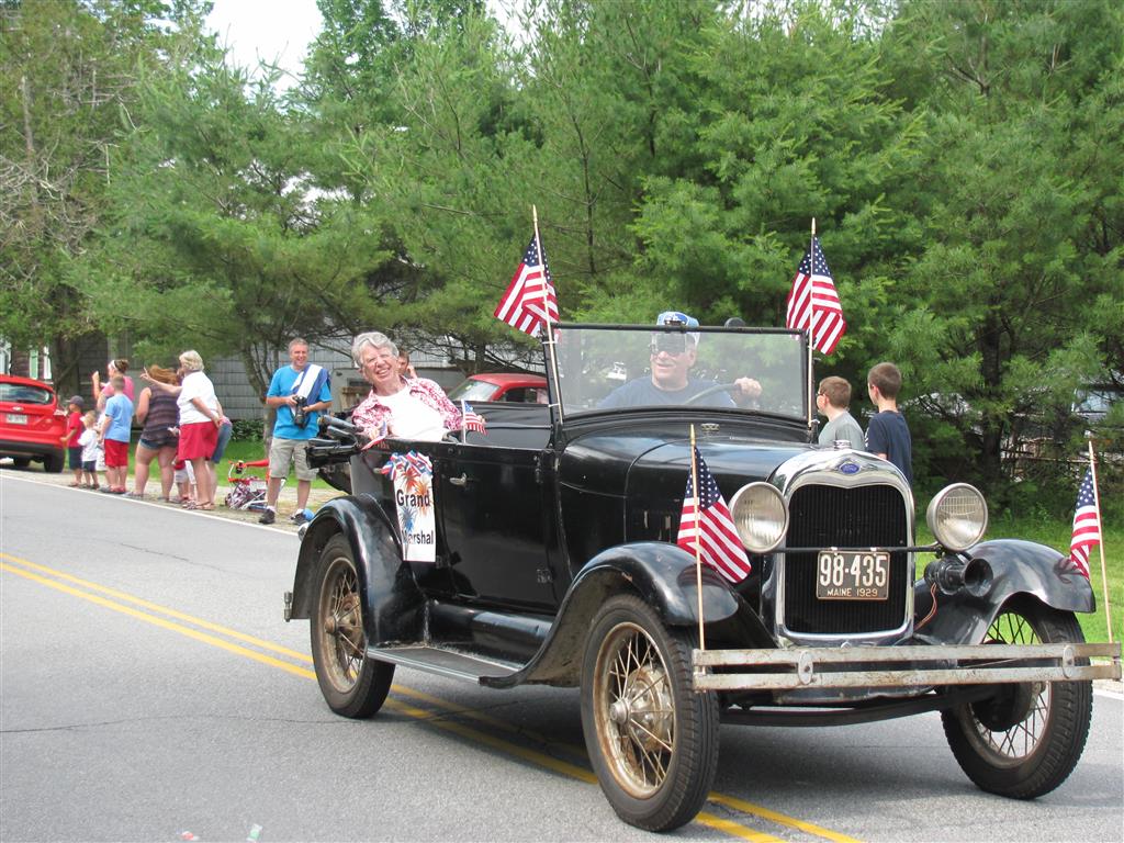 Black antique touring car with American flags at the Fourth of July parade.