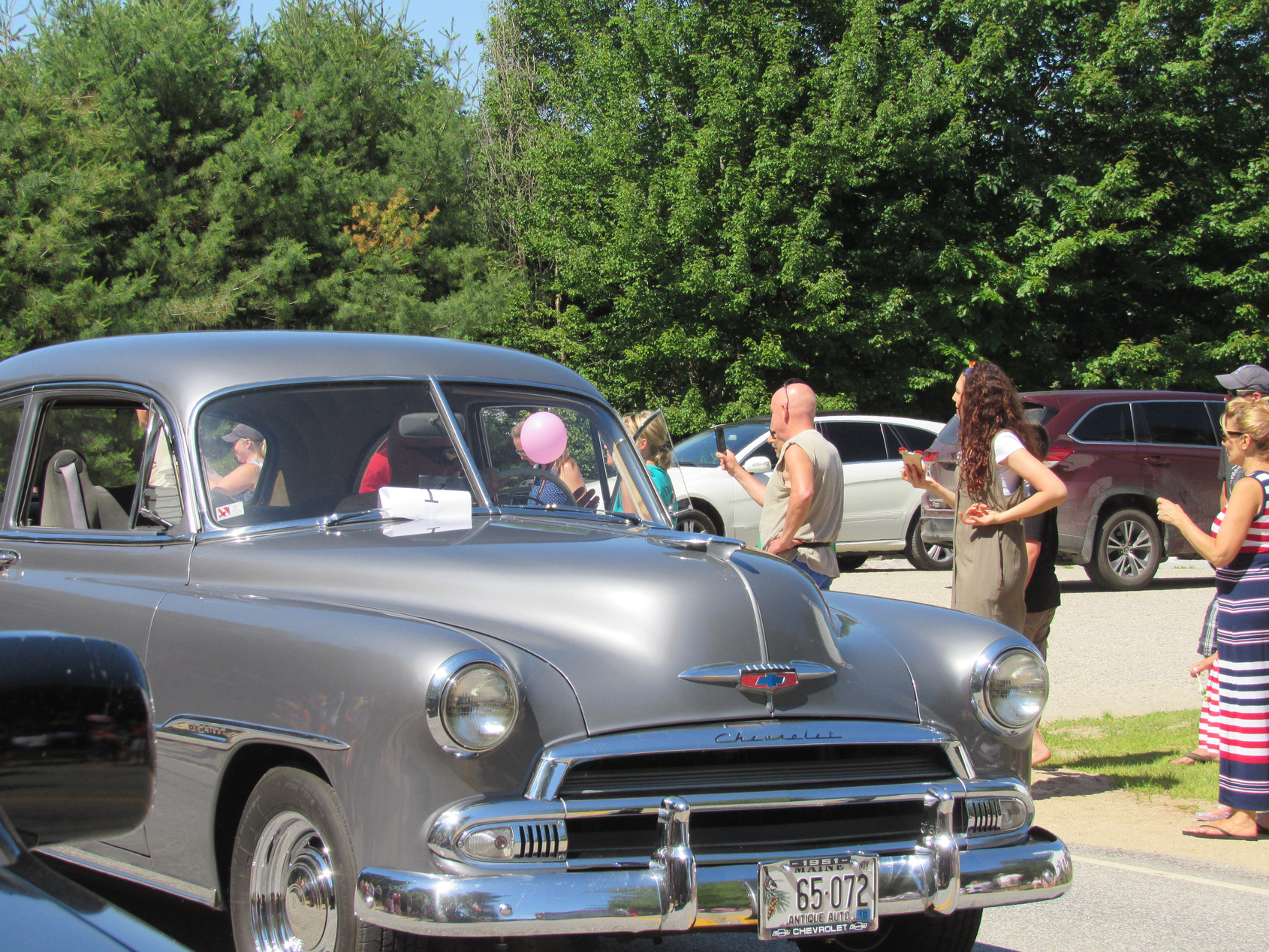 Antique passenger car passing parade spectators at the Fourth of July parade.