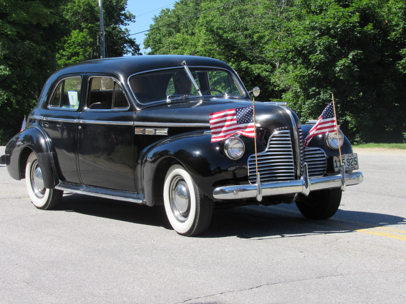 Antique passenger car passing parade spectators at the Fourth of July parade.
