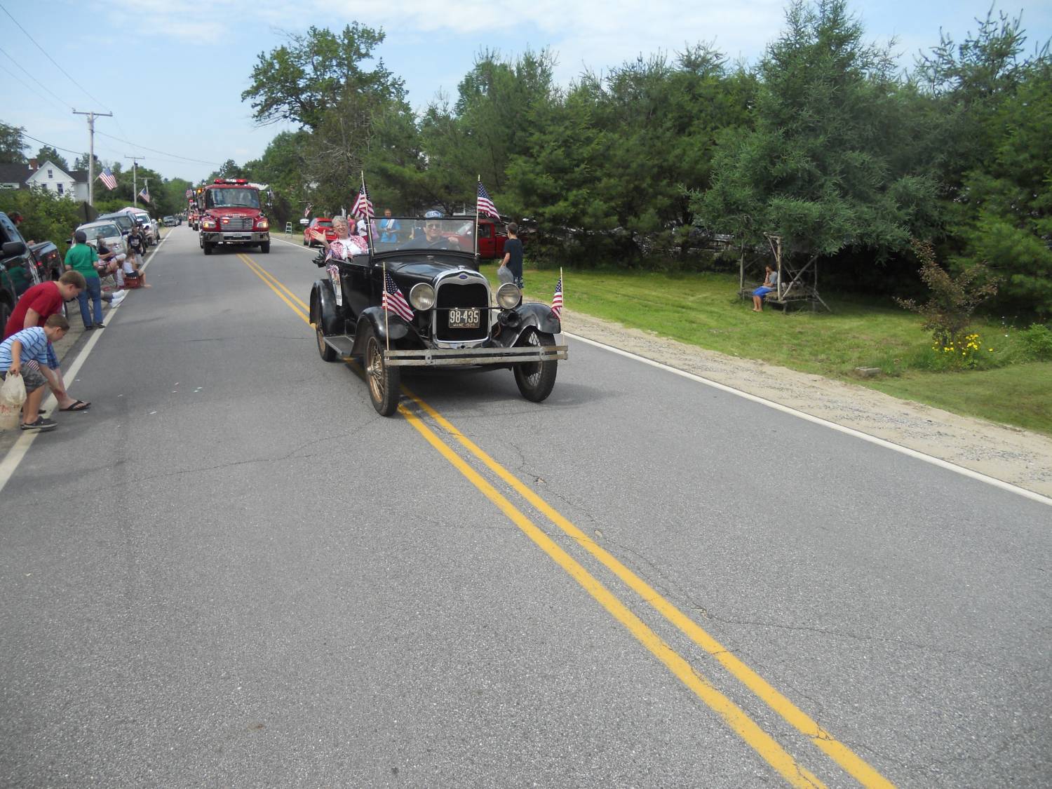Black antique touring car with American flags at the Fourth of July parade.