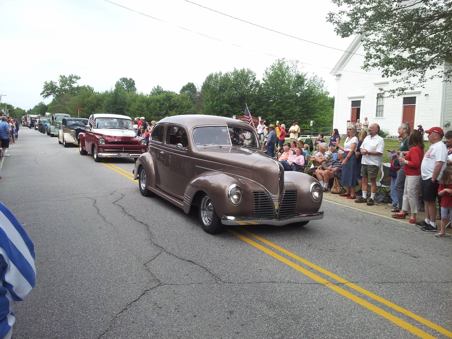 Antique passenger car passing parade spectators at the Fourth of July parade.