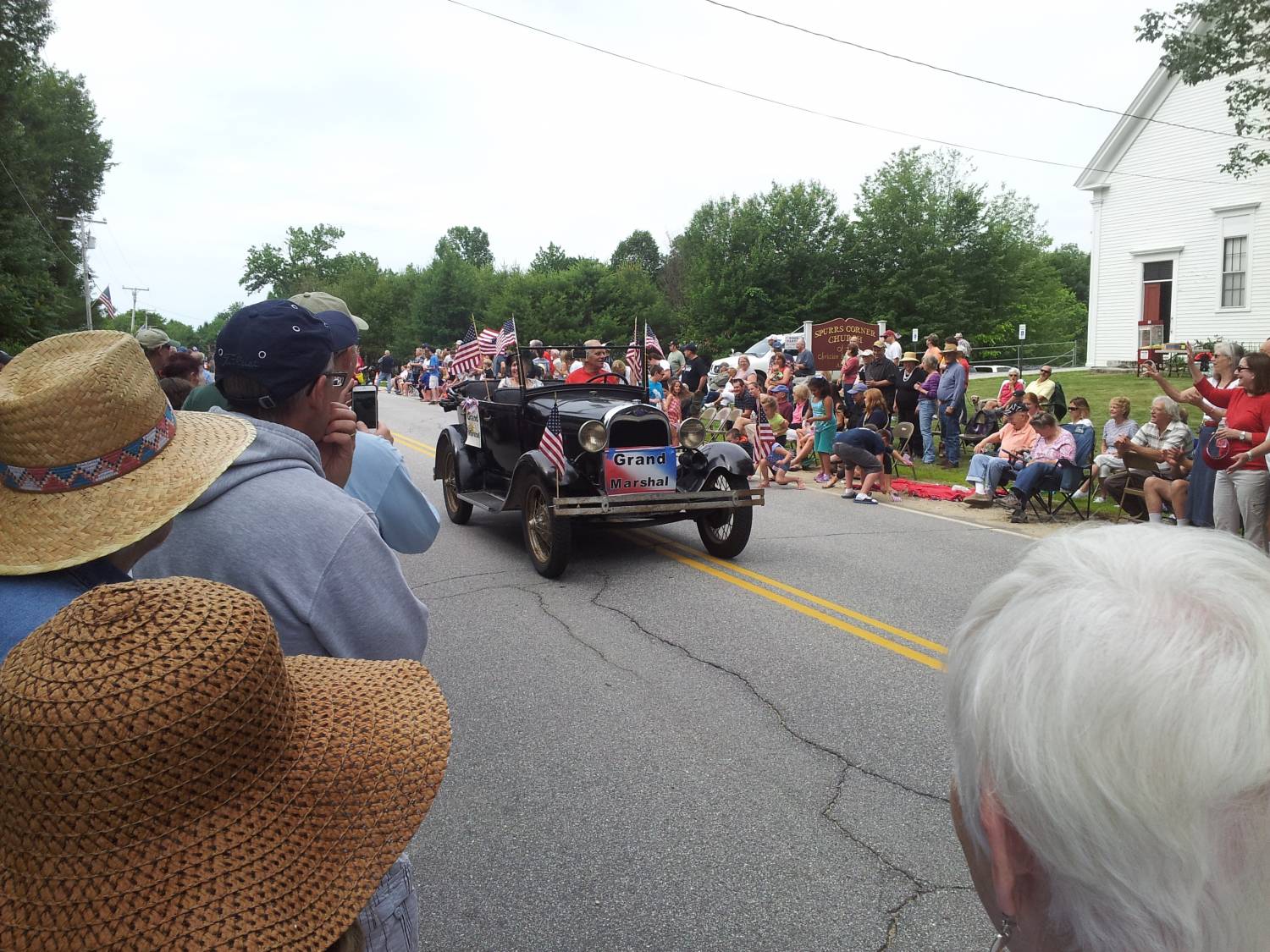 Black antique touring car with American flags at the Fourth of July parade.