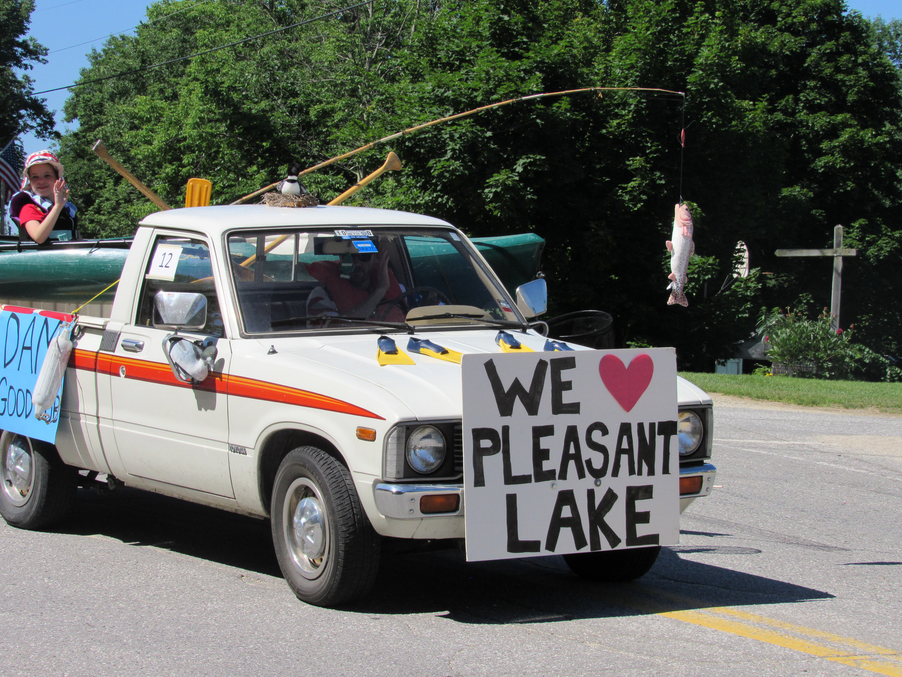 Pickup truck carrying a canoe and Pleasant Lake signs at the Fourth of July parade.