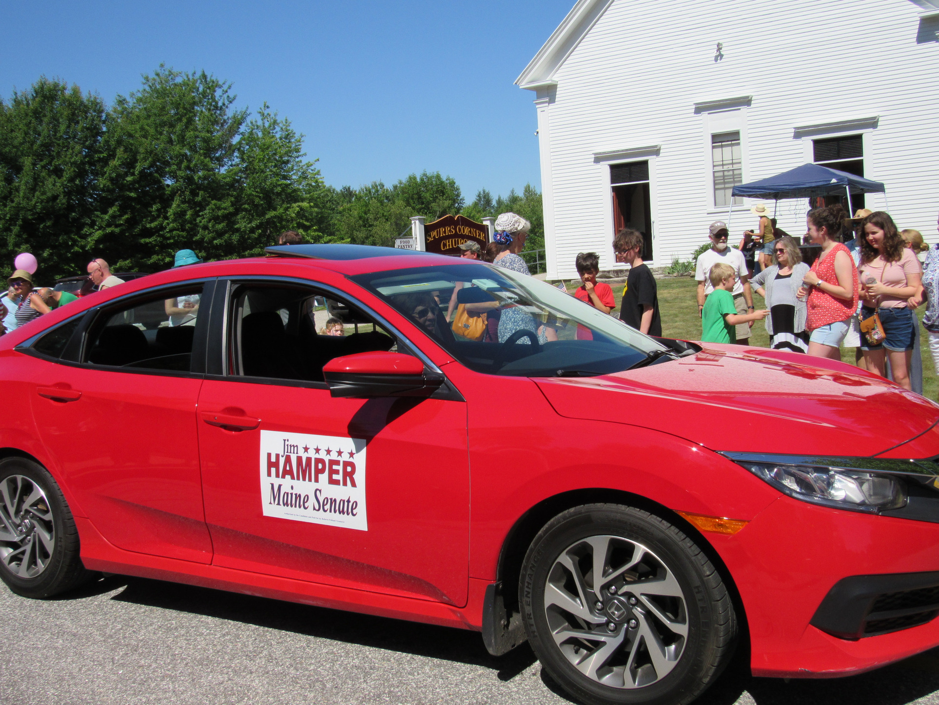 Red car carrying a Jim Hamper Maine Senate sign at the Fourth of July parade.