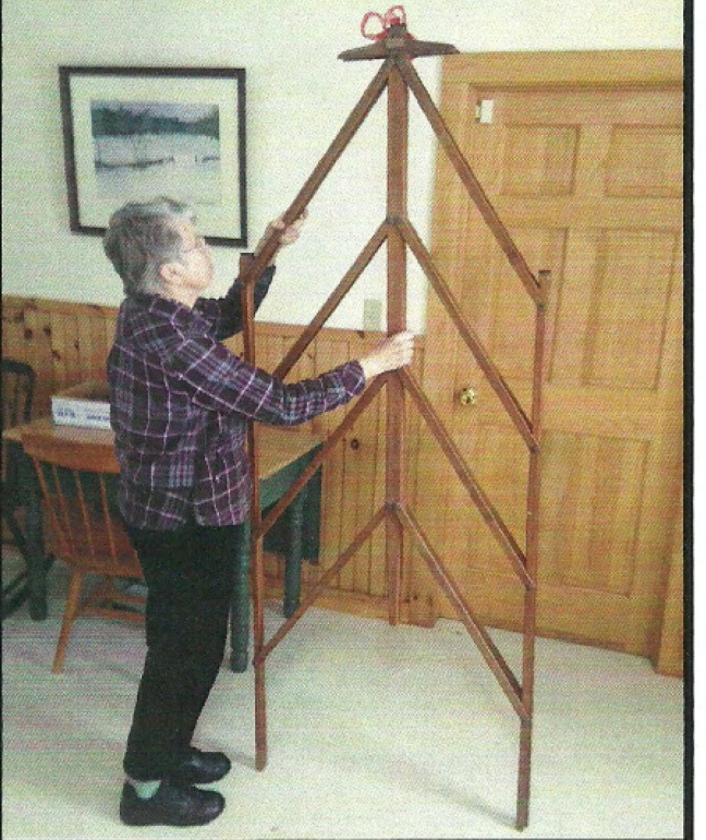 Jean Hankins trying to unfold antique quilt rack donated by Lee Dassler